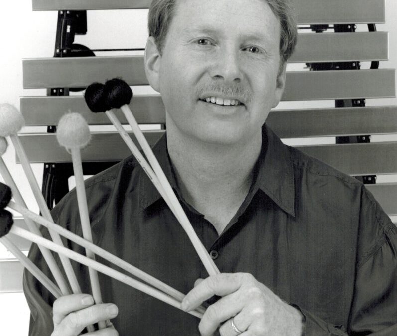 Man holding mallets near xylophone.